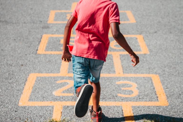 back view of young boy playing hopscotch