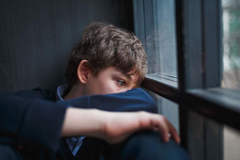 sad boy looking out of window